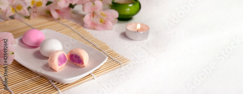 Mock up colorful japanese dessert mochi with flowers on bamboo mat. Traditional healthy sweets. Vegan confectionery. Spring or summer romantic concept.