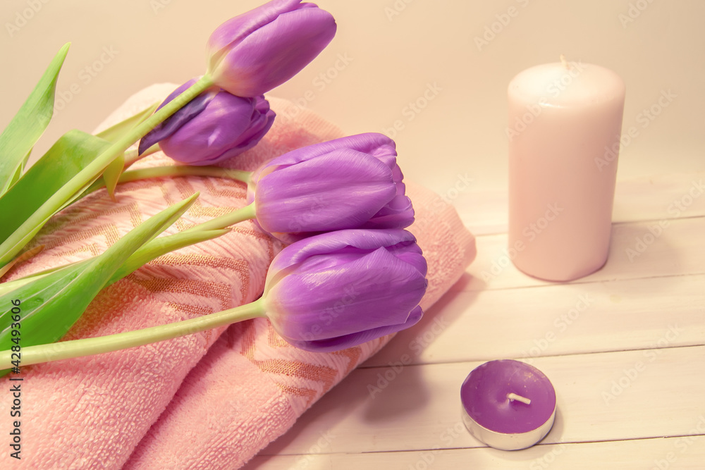 Spa still life - tulips, candles, towels on a white wooden background. Beige, pink, lilac, purple and white tones. Spa still life - tulips, candles, towels on a white wooden background. Beige, pink, lilac, purple and white tones.