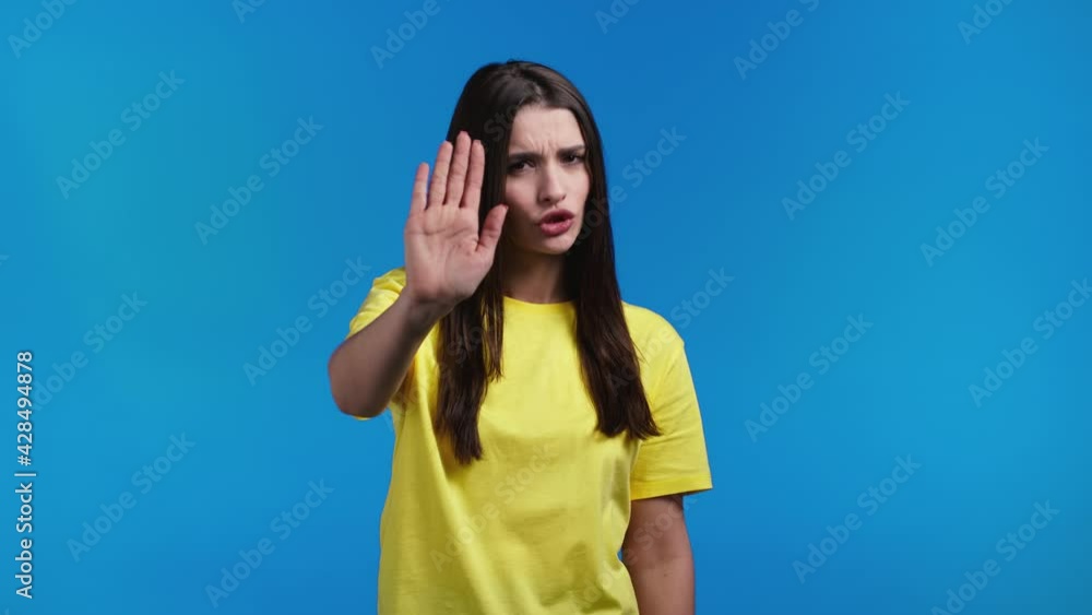 Pretty woman disapproving with no palms hands sign makes basta, negation, enough gesture. Denying, Rejecting, Disagree, Portrait of serious girl on blue background Pretty woman disapproving with no palms hands sign makes basta, negation, enough gesture. Denying, Rejecting, Disagree, Portrait of serious girl on blue background