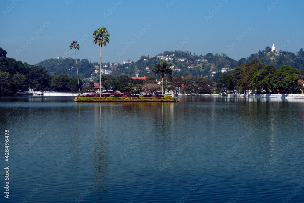 Kandy, Sri lanka, 02/13/2014: Lake Kandy with the small island in the middle, the hills in the background with the Buddha statue of Bahiravakanda on the right