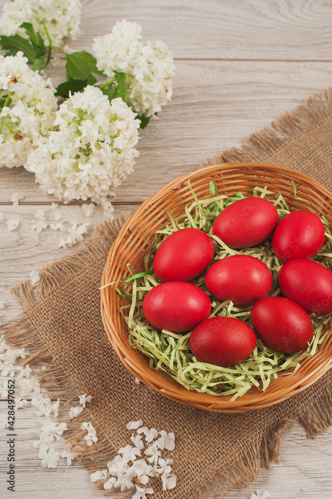 Traditional red Easter eggs in a basket on rustic wood background.