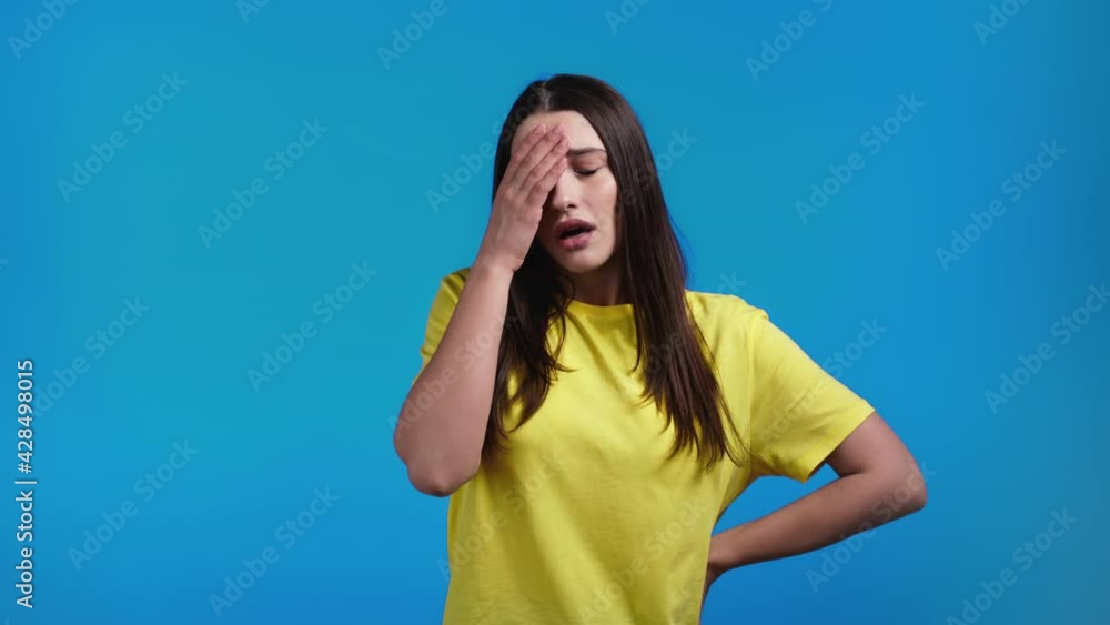 Portrait of young woman doing facepalm gesture, like no, I forgot. Unhappy woman with long hair feeling sorrow, regret, drama, failure. She isolated on blue wall Portrait of young woman doing facepalm gesture, like no, I forgot. Unhappy woman with long hair feeling sorrow, regret, drama, failure. She isolated on blue wall