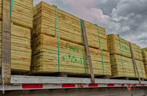 Stacks of palletized strapped down lumber planks