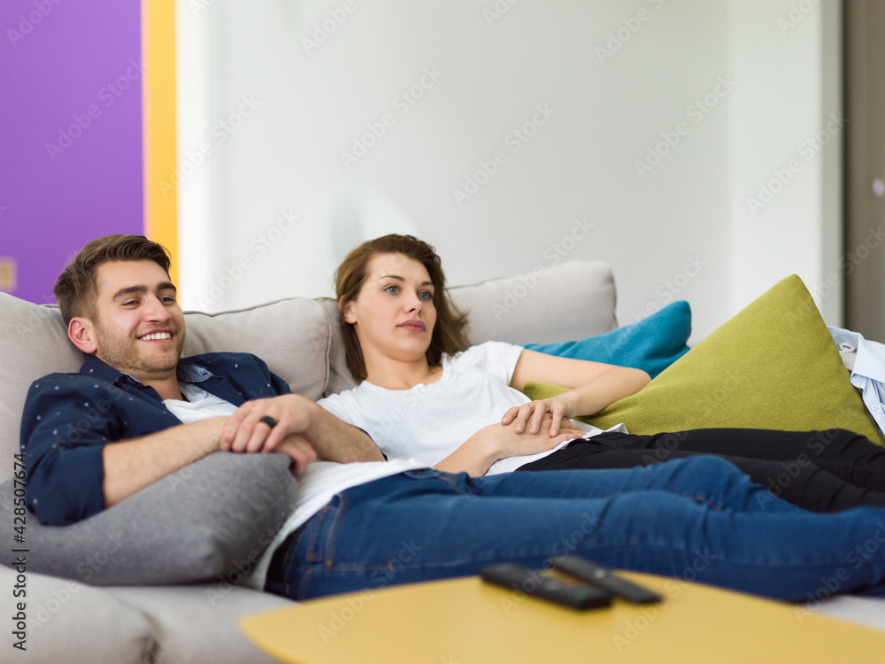 Portrait of young 25s just married couple in love posing photo shooting seated on couch in modern studio apartments