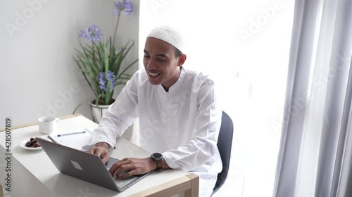 happy asian muslim man meeting using laptop for video call conference photo