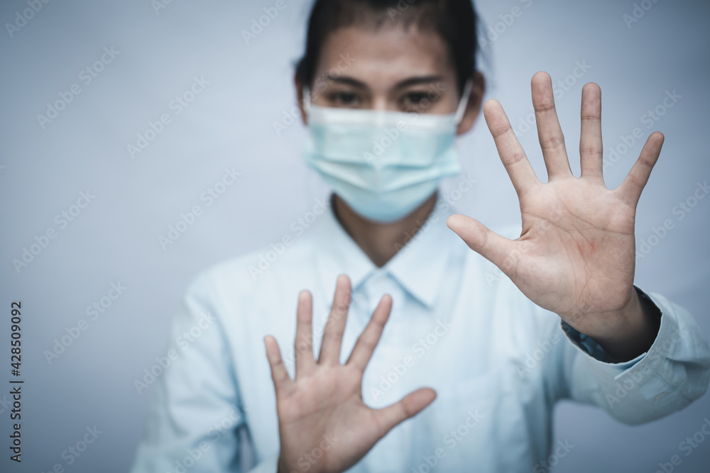 Girl wearing mask for protection from disease and show stop hands gesture for stop corona virus outbreak. Concept against coronavirus, COVID 19 Girl wearing mask for protection from disease and show stop hands gesture for stop corona virus outbreak. Concept against coronavirus, COVID 19