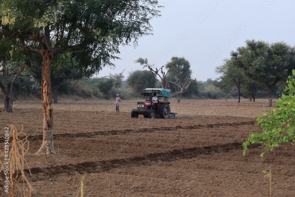 Fototapeta premium Closeup shot of Indian Farmer plowing to help the tractor in the agriculture field. concept to Organic and natural farming
