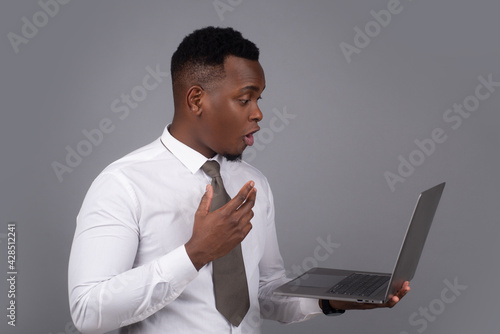 Young black businessman using laptop and taking notes at worklace in modern office,free spac photo