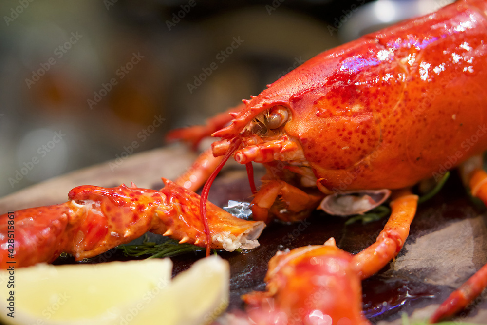 The whole lobster steamed, served with lemon on wooden plate. Close up The whole lobster steamed, served with lemon on wooden plate. Close up