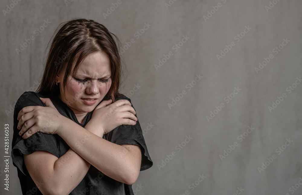 Crying teen girl hugs itself. Empty space for text Crying teen girl hugs itself. Empty space for text
