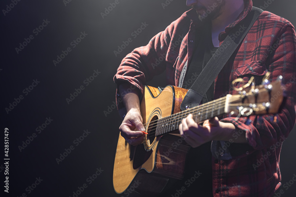 Obraz premium Acoustic guitar in the hands of a guitarist.