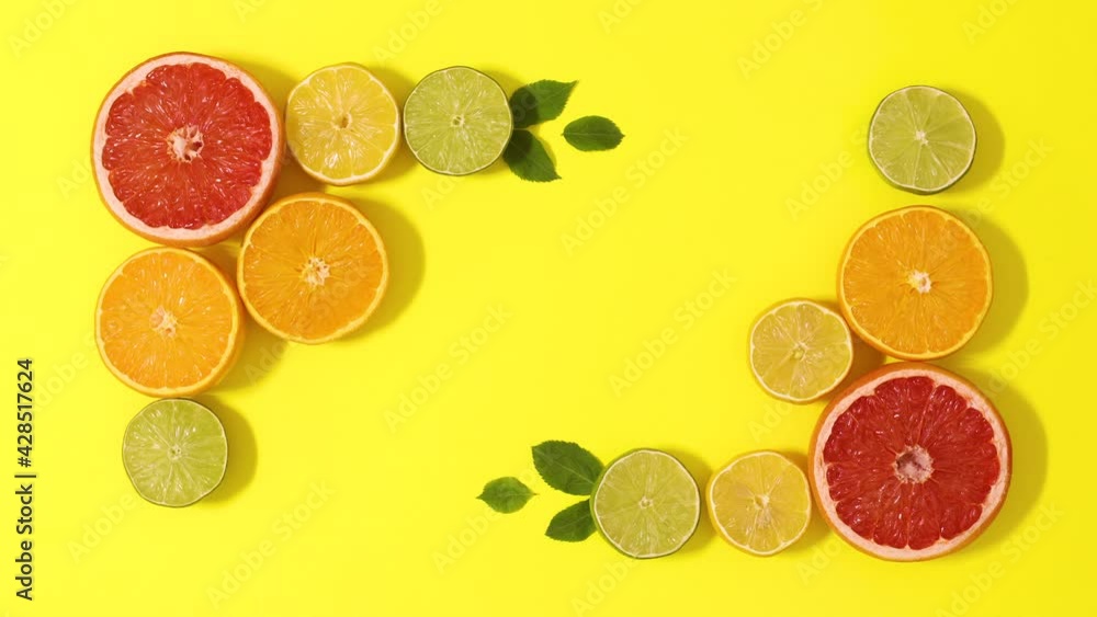 Summer frame made of sliced citrus fruits with green leaves moving on yellow background with copy space. Stop motion flat lay Summer frame made of sliced citrus fruits with green leaves moving on yellow background with copy space. Stop motion flat lay
