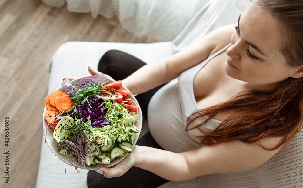 Close-up of a plate of vegetable salad in the hands of a pregnant woman. Close-up of a plate of vegetable salad in the hands of a pregnant woman.