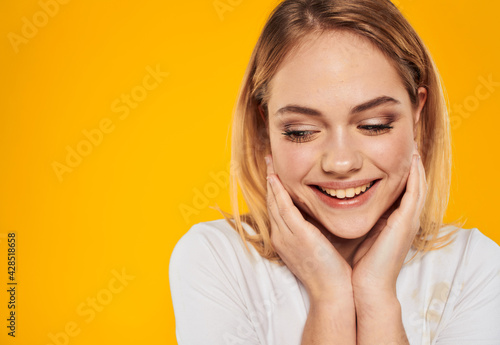 Happy blonde woman laughing on yellow background in white t-shirt cropped view © SHOTPRIME STUDIO