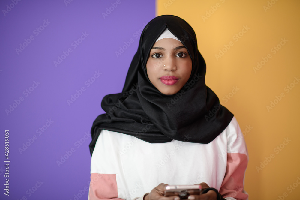 afro woman uses a cell phone in front of a pink background afro woman uses a cell phone in front of a pink background