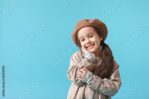 Stylish little girl in autumn clothes on color background