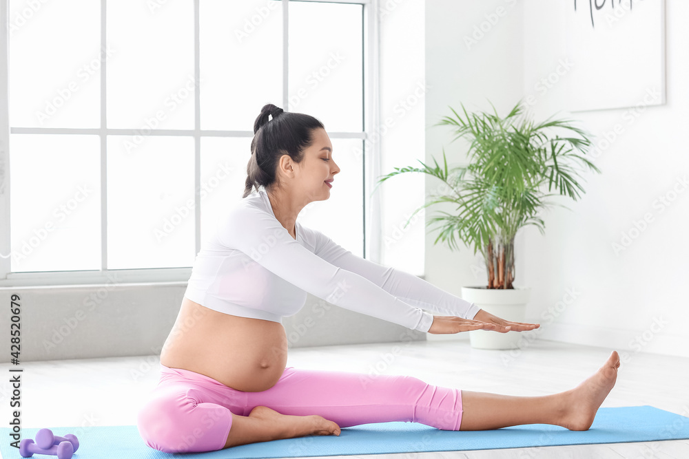 Young pregnant woman practicing yoga at home Young pregnant woman practicing yoga at home