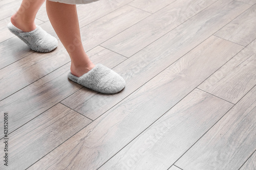 Photos Woman in slippers walking on new laminate flooring at home