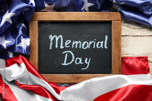 Chalkboard with text MEMORIAL DAY and USA flag on table