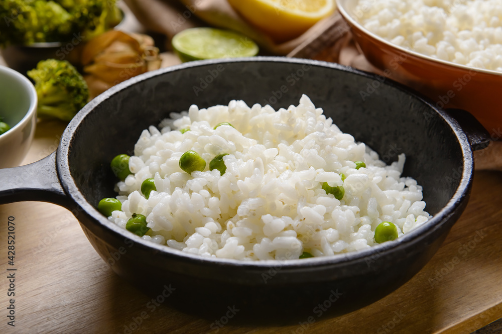 Frying pan with tasty rice on wooden background Frying pan with tasty rice on wooden background