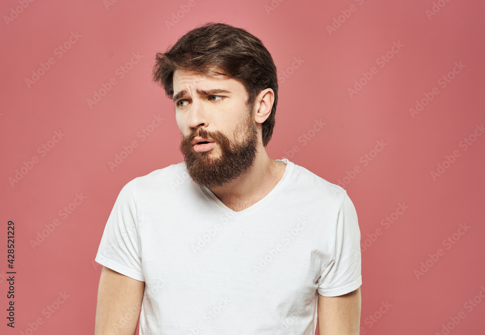 Man with a brunet beard pink background white t-shirt emotions Man with a brunet beard pink background white t-shirt emotions