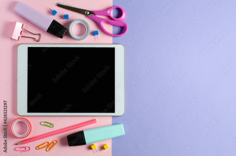 A tablet with an empty screen and office supplies on a colored background. Concept app for school children or online learning for children. Copy space A tablet with an empty screen and office supplies on a colored background. Concept app for school children or online learning for children. Copy space