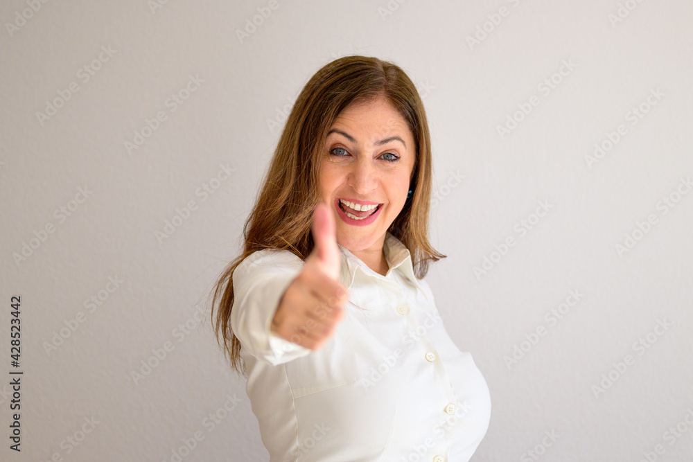 Happy exuberant middle-aged woman giving a thumbs up of success Happy exuberant middle-aged woman giving a thumbs up of success