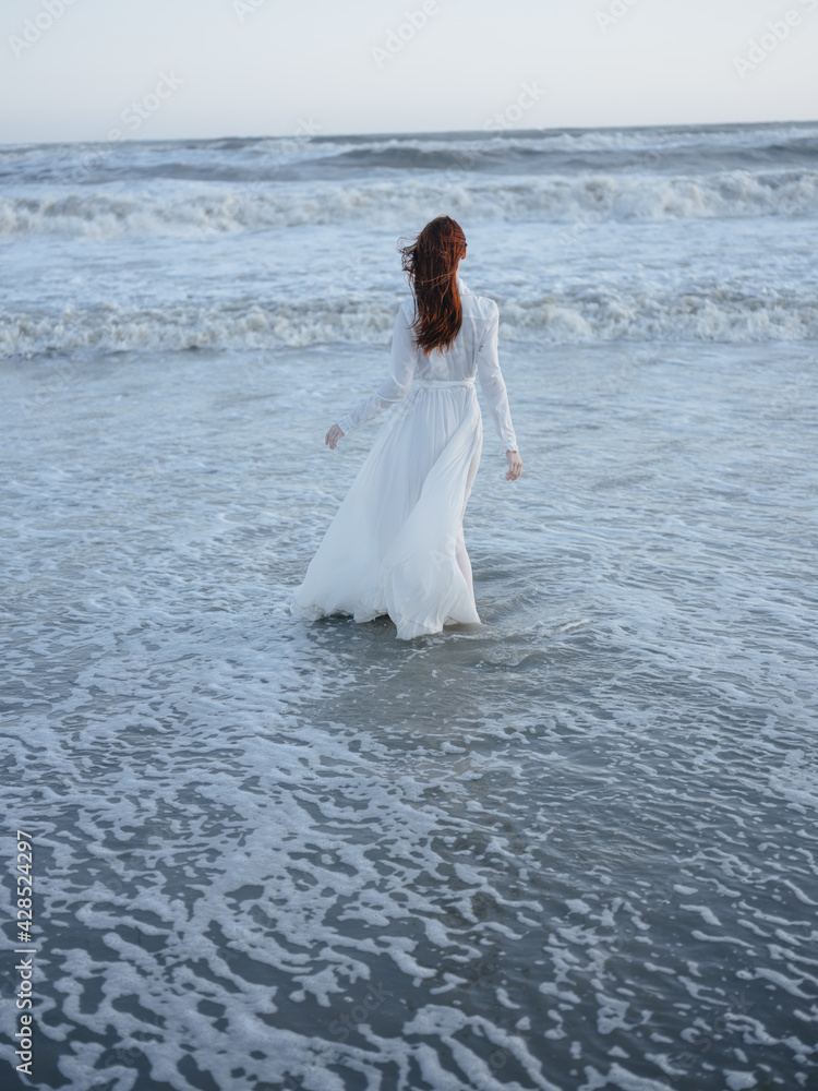 Romantic Woman in White Wedding Dress on the Beach by the Ocean Romantic Woman in White Wedding Dress on the Beach by the Ocean
