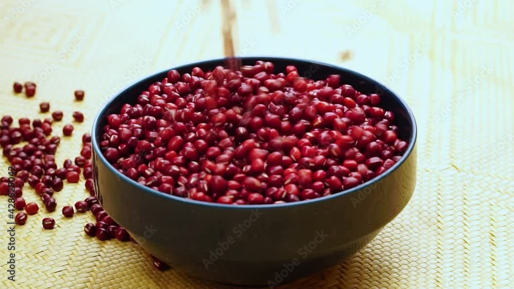 Slow motion of sprinkling red beans into a black bowl from the top Slow motion of sprinkling red beans into a black bowl from the top