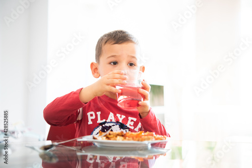 3-year-old boy about to turn 4 at the table drinking water. little boy eating