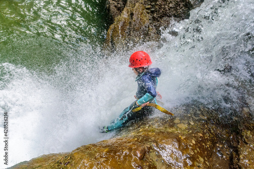 Fototapeta Naklejka Na Ścianę i Meble -  Mutprobe beim Canyoning - kleiner Junge in einer Felsrutsche im Wasserfall
