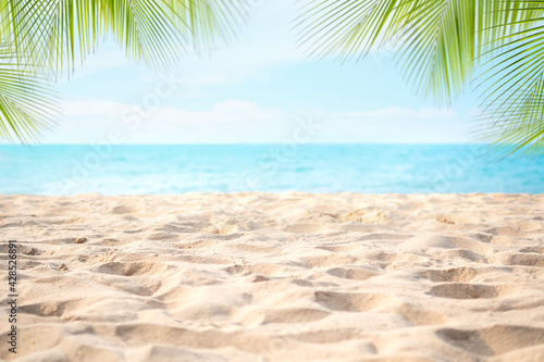 Fototapeta Naklejka Na Ścianę i Meble -  Pile sand beach with palm leaves or coconut leaves at coast and blur blue sea with bokeh with blue sky. tourist travel tropical holidays summer nature concept.