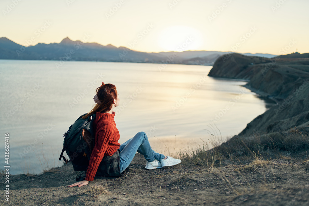 woman tourist with a backpack in the mountains at sunset near the sea top view woman tourist with a backpack in the mountains at sunset near the sea top view