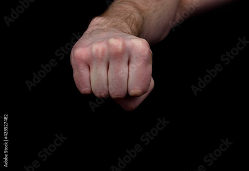 Fist of a man on a black background close-up.