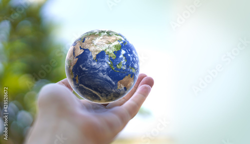 Fototapeta Naklejka Na Ścianę i Meble -  Human hand holds small Earth with care and love. Planet Earth globe ball in human hand. Strong Human  hands support planet. Earth day and saving planet. Environment conservation concept. 