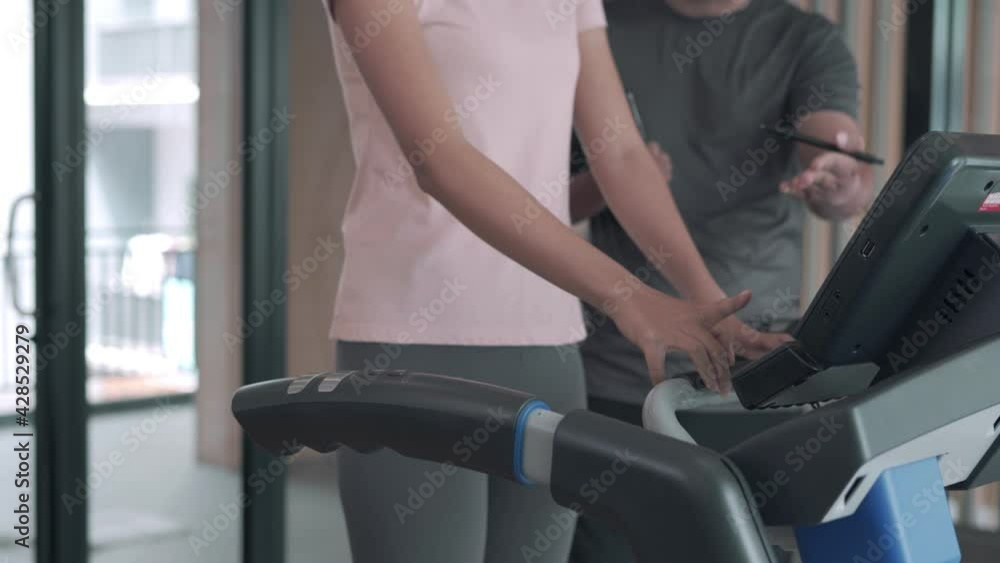 woman is exercising on a treadmill with her trainer advice and record activity details. Exercising in Fitness will be recommended to exercise properly to reduce the risk of injury to your muscles. woman is exercising on a treadmill with her trainer advice and record activity details. Exercising in Fitness will be recommended to exercise properly to reduce the risk of injury to your muscles.
