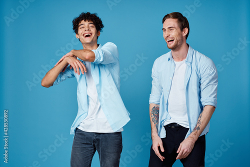 curly guy in shirt and blond man on blue background chatting friends cropped view