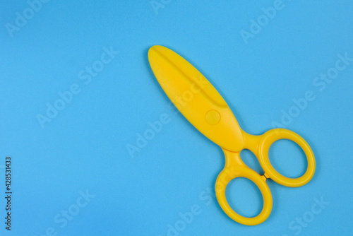 Yellow baby safety scissors on blue background