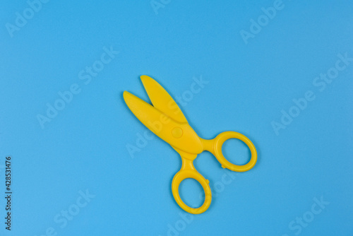 Yellow baby scissors on a blue background. Close-up.