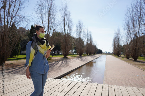 Closeup shot of a young Spanish woman wearing a face mask and taking notes outdoors photo