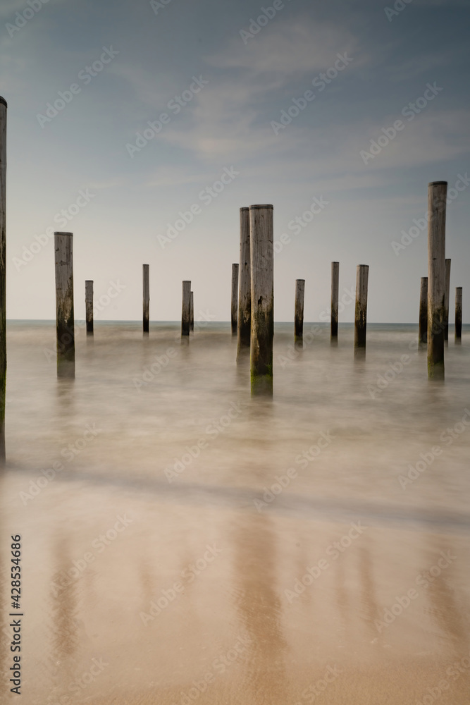 Long exposure seascape. Taken at the North Sea in Petten with the pole village in the sea, Blue sky, sun and shodows. Focus on foreground Long exposure seascape. Taken at the North Sea in Petten with the pole village in the sea, Blue sky, sun and shodows. Focus on foreground