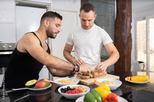 Gay couple cooking healthy vegan food together at home.