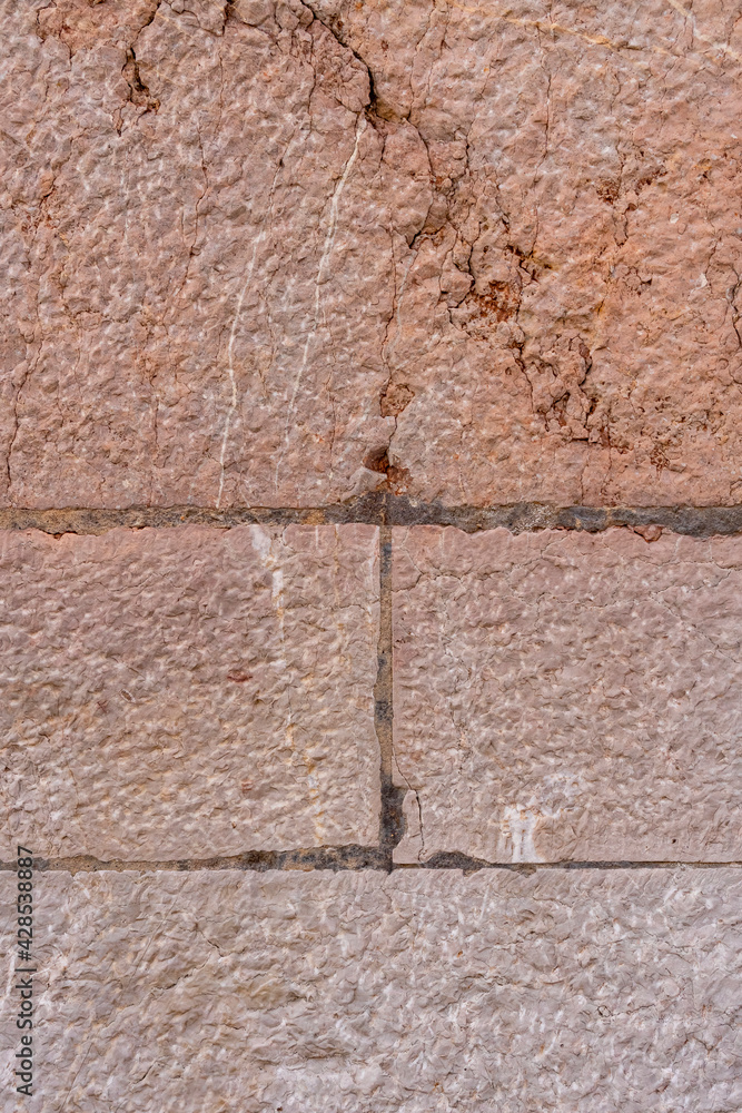 Old brown stone wall with cracks and seams Old brown stone wall with cracks and seams