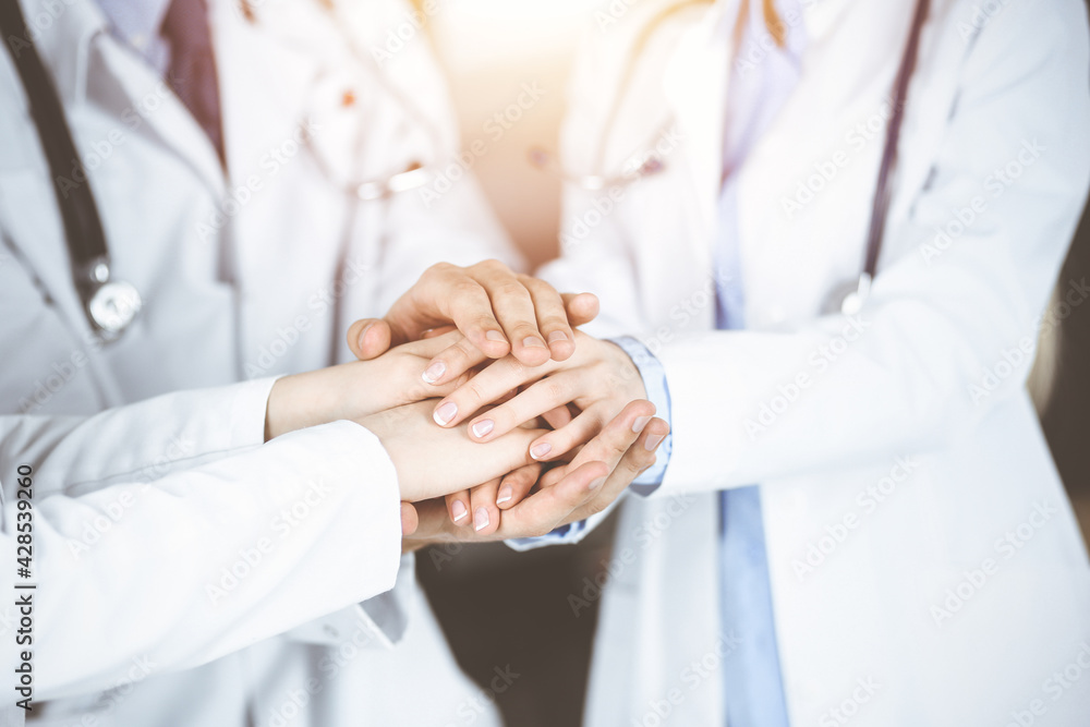Group of modern doctors joining hands as a circle. Teamwork in medicine during Coronavirus pandemic, covid 2019 Group of modern doctors joining hands as a circle. Teamwork in medicine during Coronavirus pandemic, covid 2019
