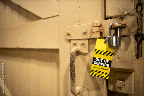 Safe workplaces practices yellow out of service warning tag placing on damaged faulty lock key on the wandle door frame equipment 