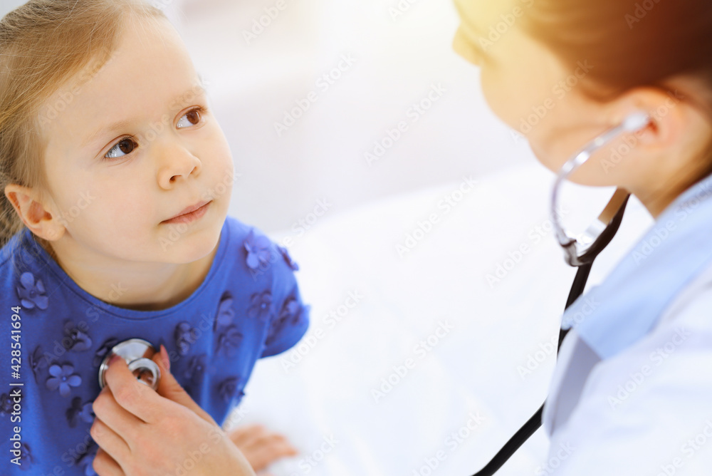 Doctor examining a little girl by stethoscope. Happy smiling child patient at usual medical inspection. Medicine and healthcare concepts Doctor examining a little girl by stethoscope. Happy smiling child patient at usual medical inspection. Medicine and healthcare concepts