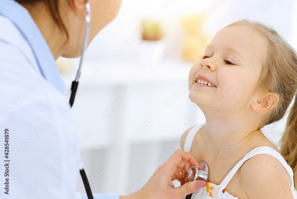 Doctor examining a little girl by stethoscope. Happy smiling child patient at usual medical inspection. Medicine and healthcare concepts Doctor examining a little girl by stethoscope. Happy smiling child patient at usual medical inspection. Medicine and healthcare concepts