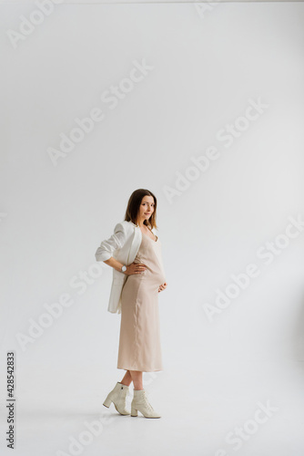 Beautiful young pregnant woman in a dress in the studio. © Oksana