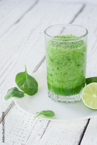 Empty space for text. Healthy lifestyle. Celery, spinach and lime smoothie. Drink glass, lime, spinach leaves. Vertical photo.