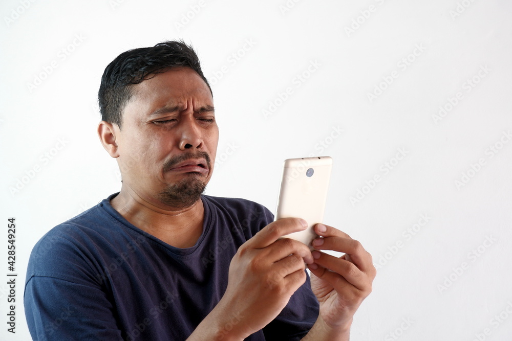 sad man crying looking at the phone, funny upset reaction asian guy with smartphone, unhappy feeling of men sad man crying looking at the phone, funny upset reaction asian guy with smartphone, unhappy feeling of men